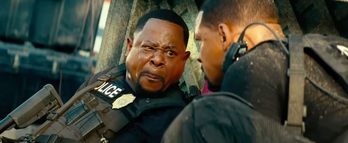 Martin Lawrence makes a really weird “I gotta poop” face, lips pressed together, cheeks puffed out, sweat on his forehead, and one eye squinted as he looks over at Will Smith in Bad Boys: Ride or Die