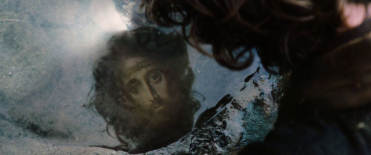 A man staring into a pool of water at an image of Jesus Christ reflecting back at him in Silence.