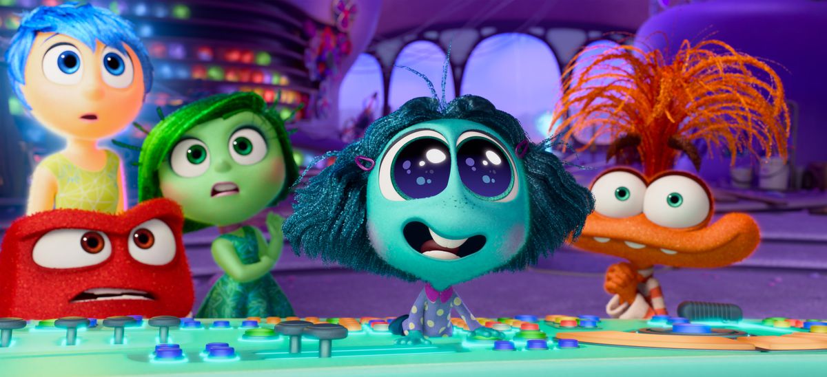 En ny känsla, den akvamarinskinnade Envy (Ayo Edebiri), tar konsolen i Rileys huvud och svarar på något utanför skärmen med stora ögon och ett strålande leende i Pixar Animation Studios Inside Out 2