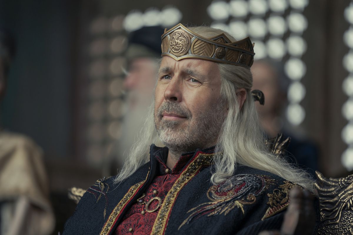 Viserys chillar direkt med en krona på huvudet och kungliga trådar, tittar på en turnering utanför skärmen på House of the Dragon