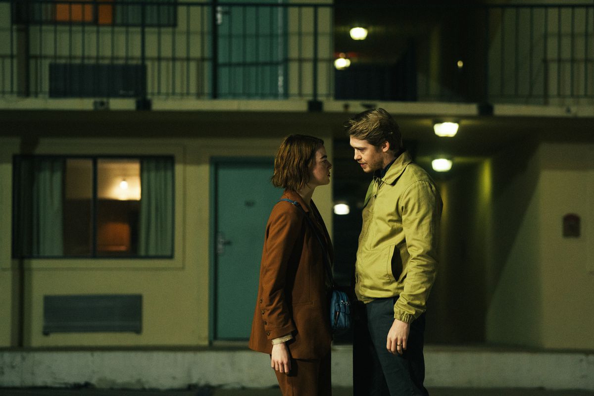 Emma Stone och Joe Alwyn står nära varandra på en motellparkering på natten i Kinds of Kindness