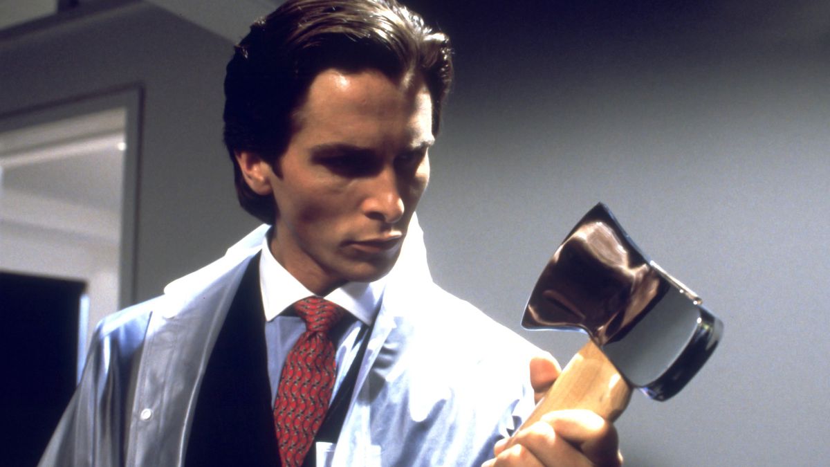 Patrick Bateman (Christian Bale) håller i en yxa när han bär en kostym under en plastponcho i American Psycho