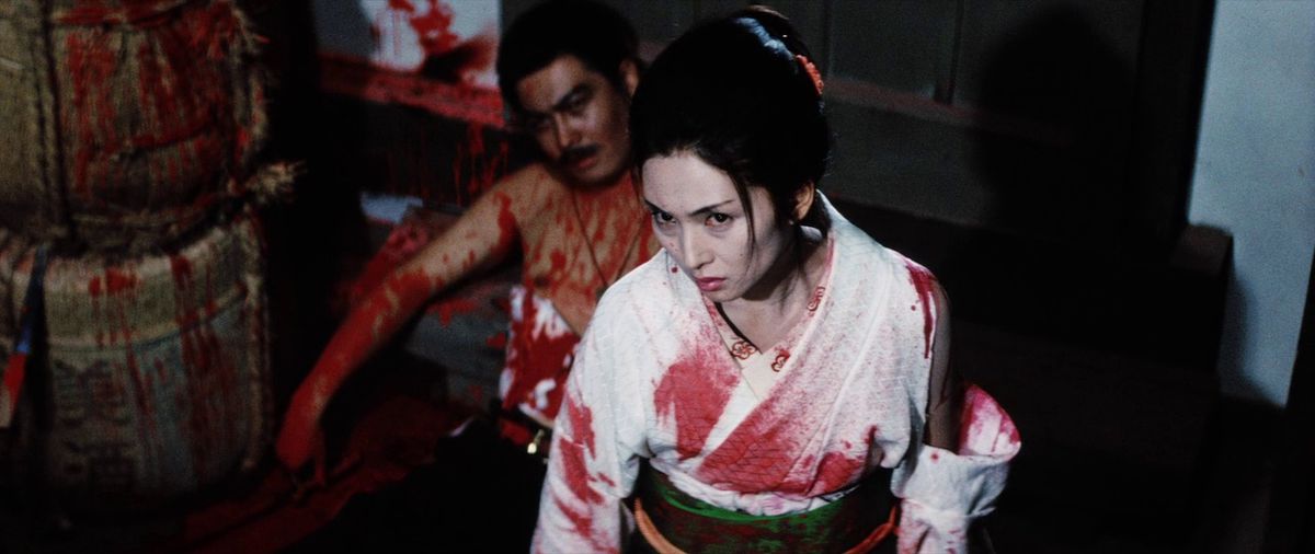 Meiko Kaji, covered in blood, stands next to a bloody corpse in Lady Snowblood