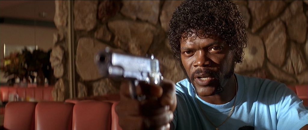 Samuel L. Jackson holds a gun in a diner booth in Pulp Fiction