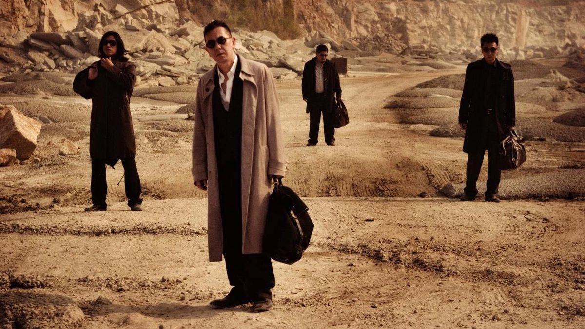 The very cool-looking hitmen from Exiled stand in a desert with bags and guns