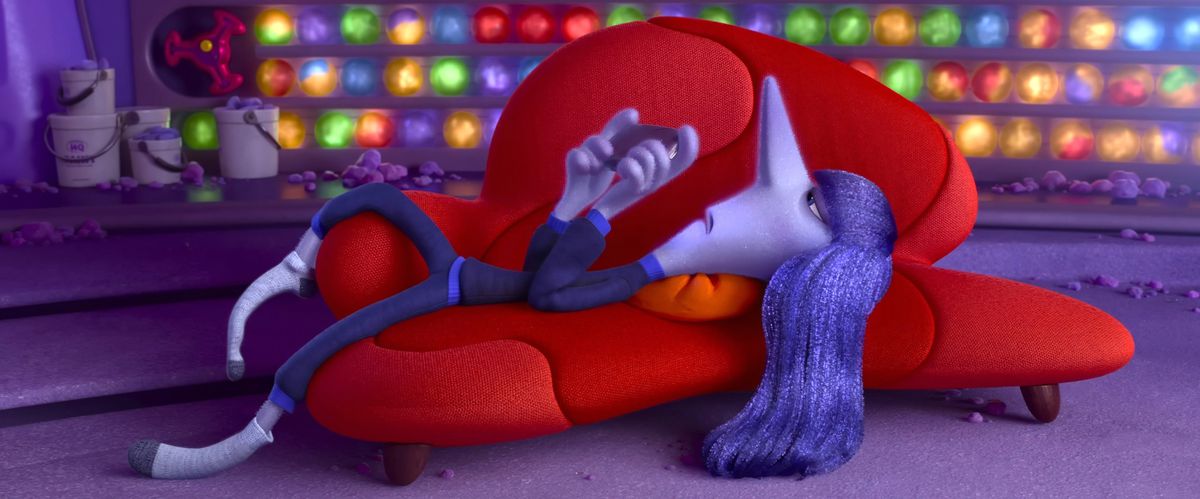 Ennui ligger på rygg i en knallröd soffa, ser irriterad ut och leker med sin telefon, i en scen från Pixar Animation Studios Inside Out 2